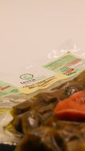 Lade das Bild in den Galerie-Viewer, Eine vakuumversiegelte Packung Terramia Olive schiacciate alla giardiniera 500 g mit italienischer Aufschrift liegt auf einer weißen Fläche. Das Etikett ist scharf abgebildet, während das marinierte Gemüse im Vordergrund leicht verschwommen erscheint.