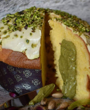 Lade das Bild in den Galerie-Viewer, Nahaufnahme von Nove Panettone al Pistacchio, gefüllt mit Pistaziencreme, aufgeschnitten, um die grüne Pistaziencremefüllung zu enthüllen, überzogen mit weißem Zuckerguss und gehackten Pistazien, mit einem Kuchenmesser und ganzen Pistazien im Vordergrund.