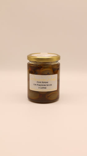 Ein Glas Conserve Conti Gefüllte Oliven mit getrockneten Tomaten und Kapern in nativem Olivenöl extra 270g steht auf einem beigen Hintergrund - ideal als sizilianische Antipasti.