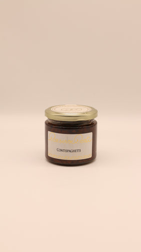 Ein Glasgefäß mit goldenem Deckel, gefüllt mit dunkelroten Contispaghetti - Pesto di pomodori secchi (90g/190g) von Conserve conti, steht vor einem einfarbig beigen Hintergrund.