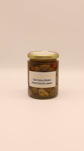 Ein Glas mit Conserve Conti Olive della Nonna denocciolate a mano - 270 g, mit sizilianischen Oliven in nativem Olivenöl extra und einem goldenen Deckel, auf einem schlichten, hellen Hintergrund.