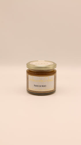 Ein kleines Glas mit goldenem Deckel enthält Conserve Conti Pesto di noci con olio extravergine di oliva (190 g). Das weiße Etikett mit goldener und blauer Schrift hebt sich von einem schlichten beigen Hintergrund ab.
