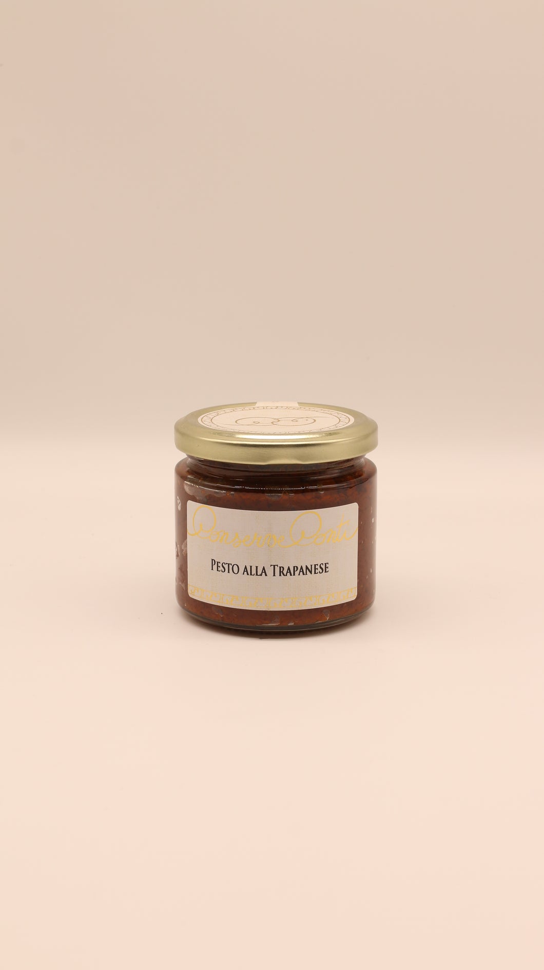 Ein Glas mit Conserve conti Pesto alla Trapanese - 190 g steht in der Mitte eines beigen Hintergrunds, auf dem Mandeln wie bei traditionellem sizilianischem Pesto aus Trapani abgebildet sind, mit einem goldenen Deckel und einem Produktetikett.