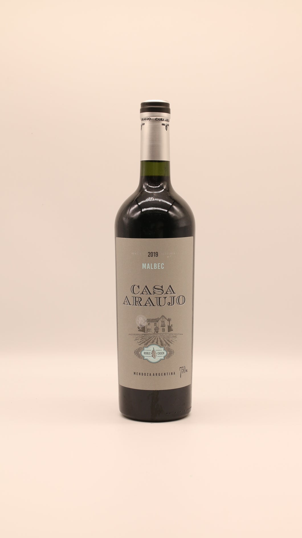 Eine Flasche Malbec Roble Casck 2019 (0,75 l) von Bodega Araujo, Argentinien, steht aufrecht vor einem schlichten, hellen Hintergrund. Das Etikett zeigt eine Illustration des Hauses mit türkisfarbenen Akzenten und hebt die Herkunft aus Mendoza hervor.