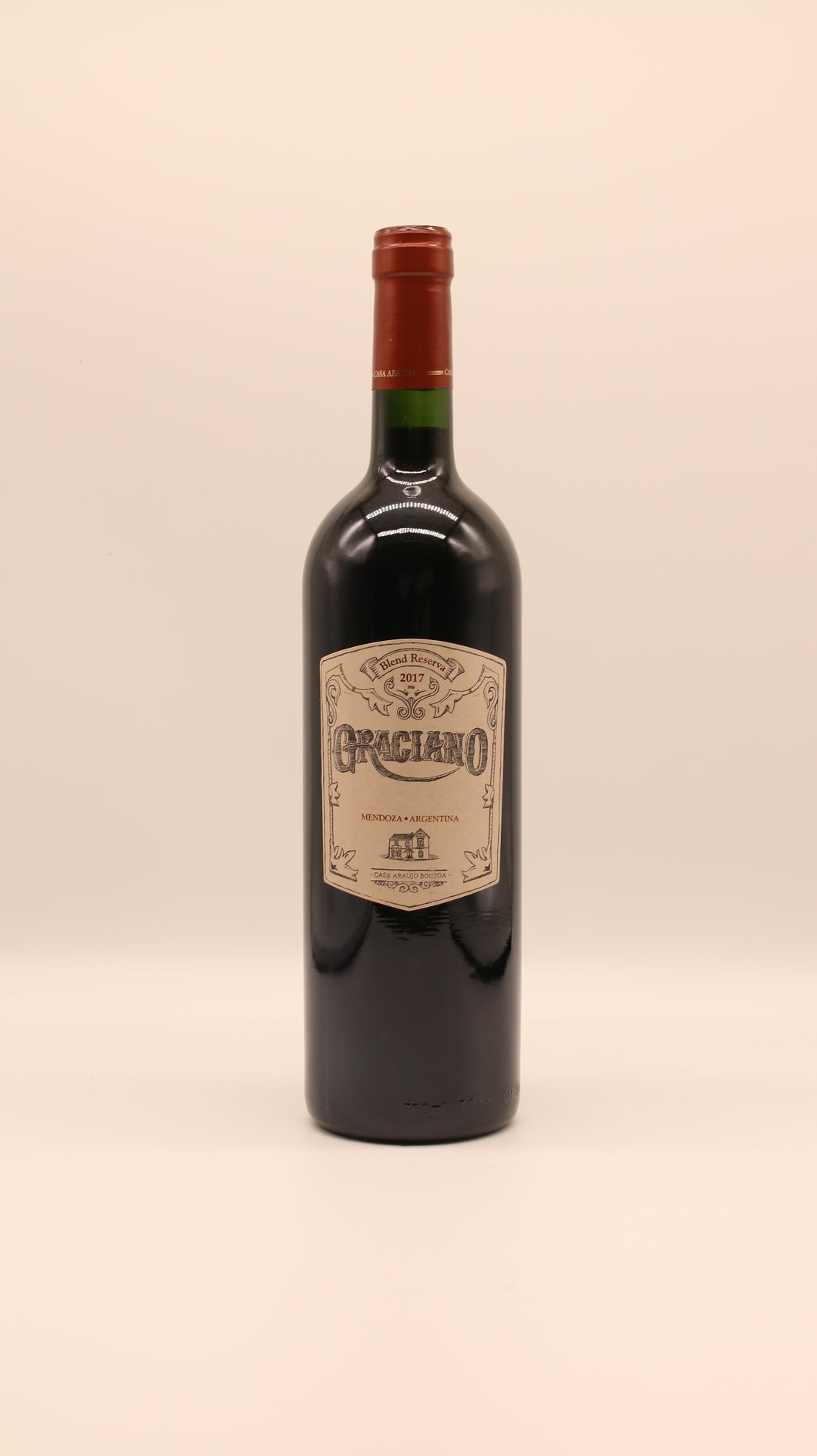 Eine Flasche Graciano Reserva Blend 2017 (0,75 l) von Bodega Araujo, Argentinien, mit rotem Foliendach und beigem Etikett steht vor einem schlichten, hellen Hintergrund, der an eine klassische Mendoza Reserva erinnert.