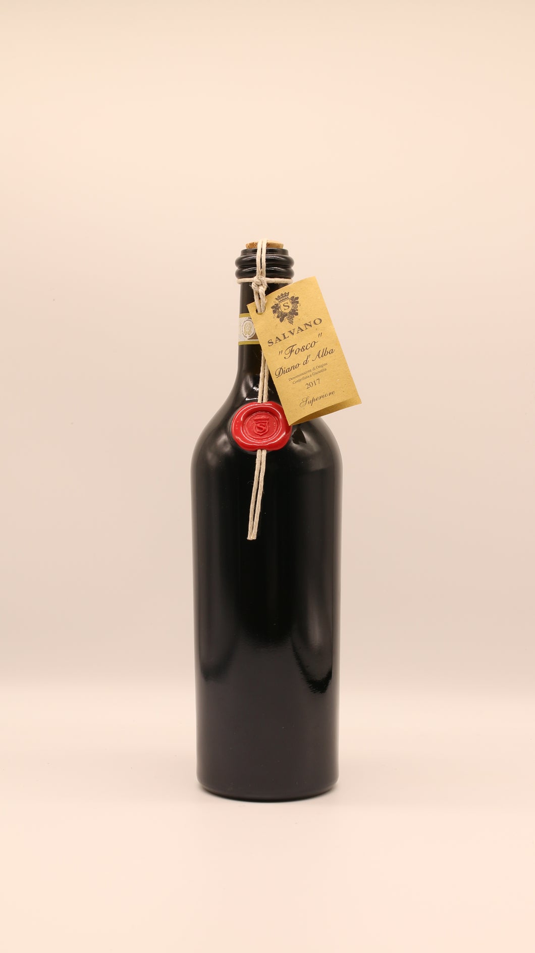 Eine dunkle Salvano-Bordeauxflasche, ein goldenes Etikett an einer Schnur und ein rotes Wachssiegel, steht aufrecht vor einem hellen Hintergrund - ein elegantes Display für den DIANO ALBA 