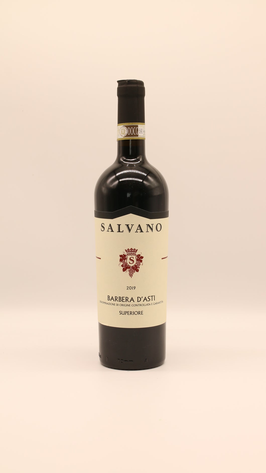 Eine Flasche Salvano BARBERA ASTI SUPERIORE 2019 DOCG mit einem cremefarbenen Etikett mit goldenen Akzenten steht aufrecht vor einem schlichten hellen Hintergrund.
