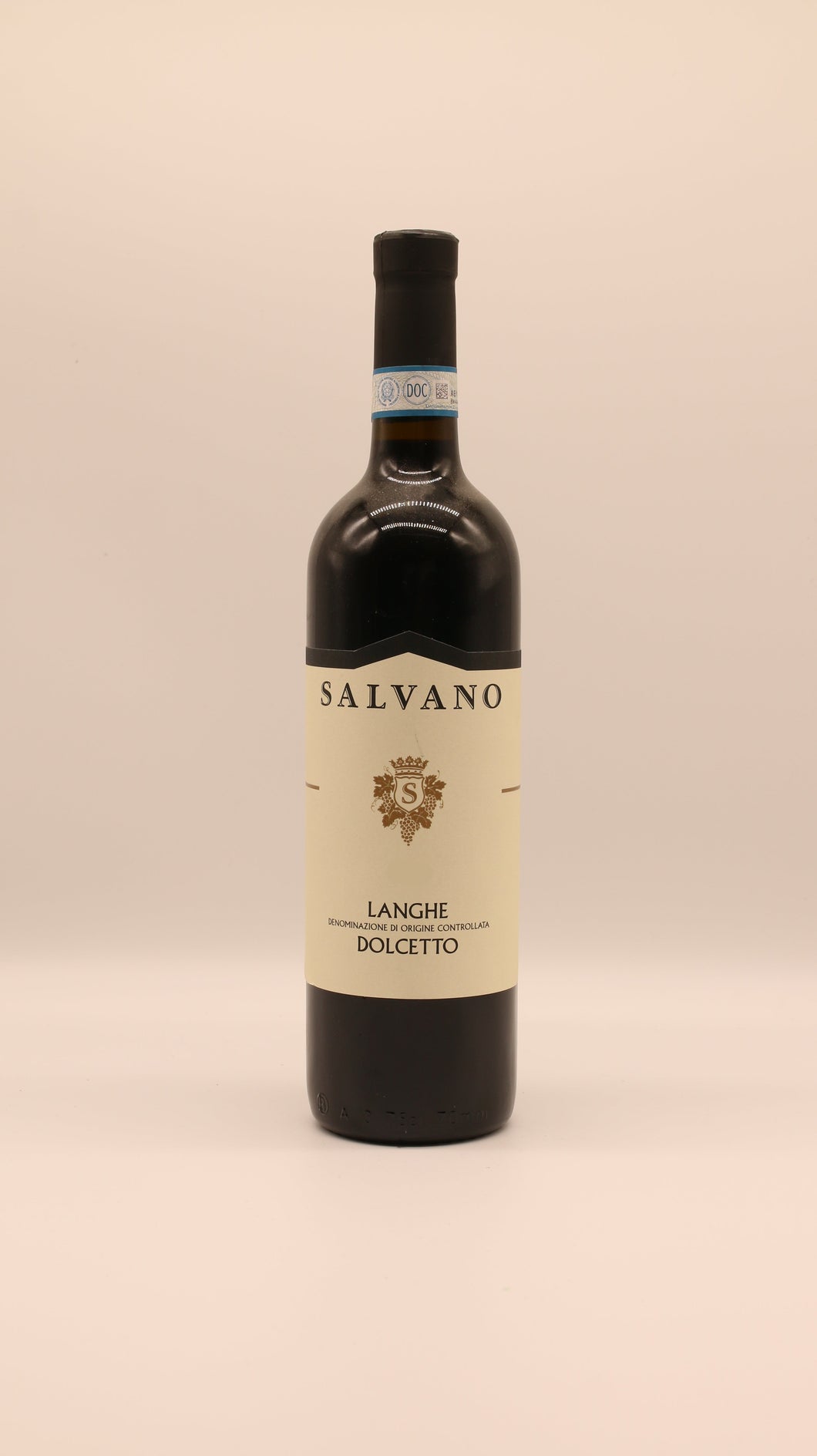 Eine Flasche Salvano LANGHE DOLCETTO 2019 DOC 0,75 Liter mit cremefarbenem Etikett und blau akzentuiertem Halsverschluss steht vor einem hellen Hintergrund.