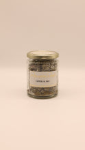 Lade das Bild in den Galerie-Viewer, Ein Glasgefäß mit goldenem Deckel und der Aufschrift Capperi al sale by Conserve conti, gefüllt mit sizilianischen Kapern in Meersalz, vor einem schlichten, hellbeigen Hintergrund.
