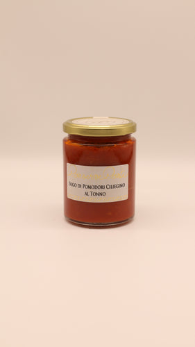 Ein Glas mit einem goldenen Deckel mit Conserve Conti Sugo di Pomodoro Ciliegino al Tonno (270 g) steht in der Mitte vor einem einfarbig beigen Hintergrund. Auf dem Etikett steht der Produktname auf Italienisch.