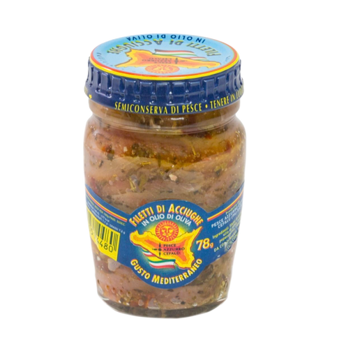 FILETTI DI ACCIUGHE OLIO OLIVA MEDITERRAN von Pesce Azzurro Srl bietet mediterranen Geschmack in einem klaren Glasgefäß mit blau-gelbem Deckel. Die Sardellenfilets in Olivenöl mit Gewürzen sind im Inneren des Glases mit italienischem Etikett sichtbar.