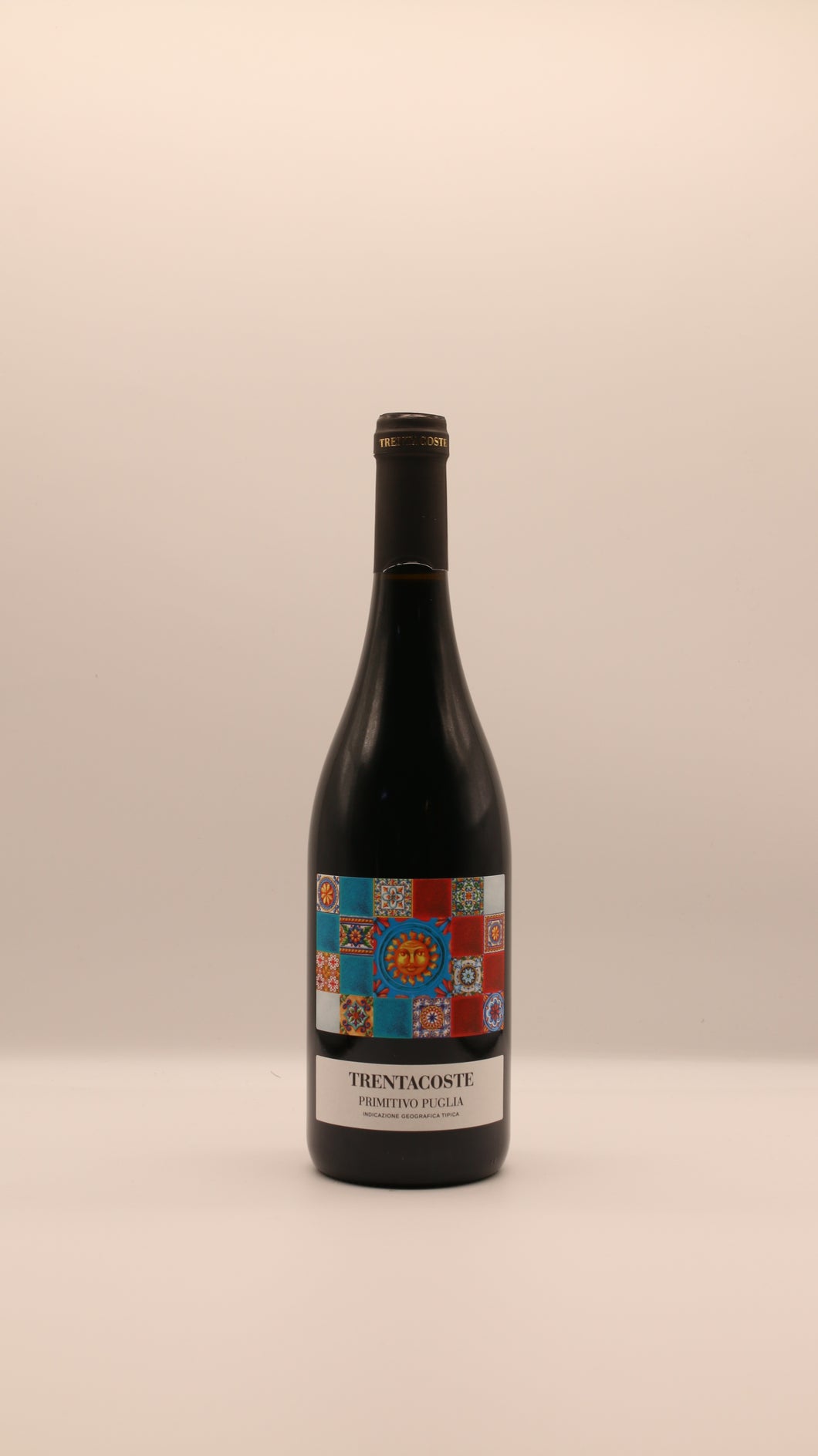 Eine Flasche TRENTACOSTE PRIMITIVO 2024 PUGLIA IGT 0,75 l von Giannis Enoteca mit einem farbenfrohen Mosaik-Etikett mit dekorativen Mustern vor einem schlichten hellen Hintergrund.